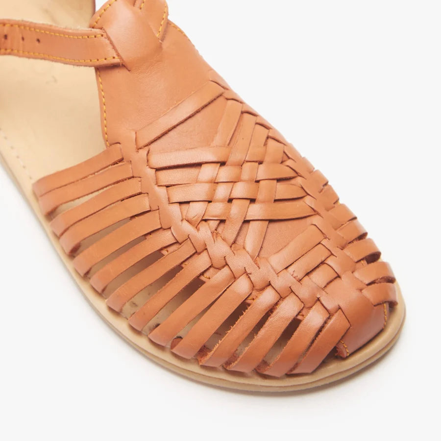 Close-up of tan braided huarache straps over an open-toe sandal upper.