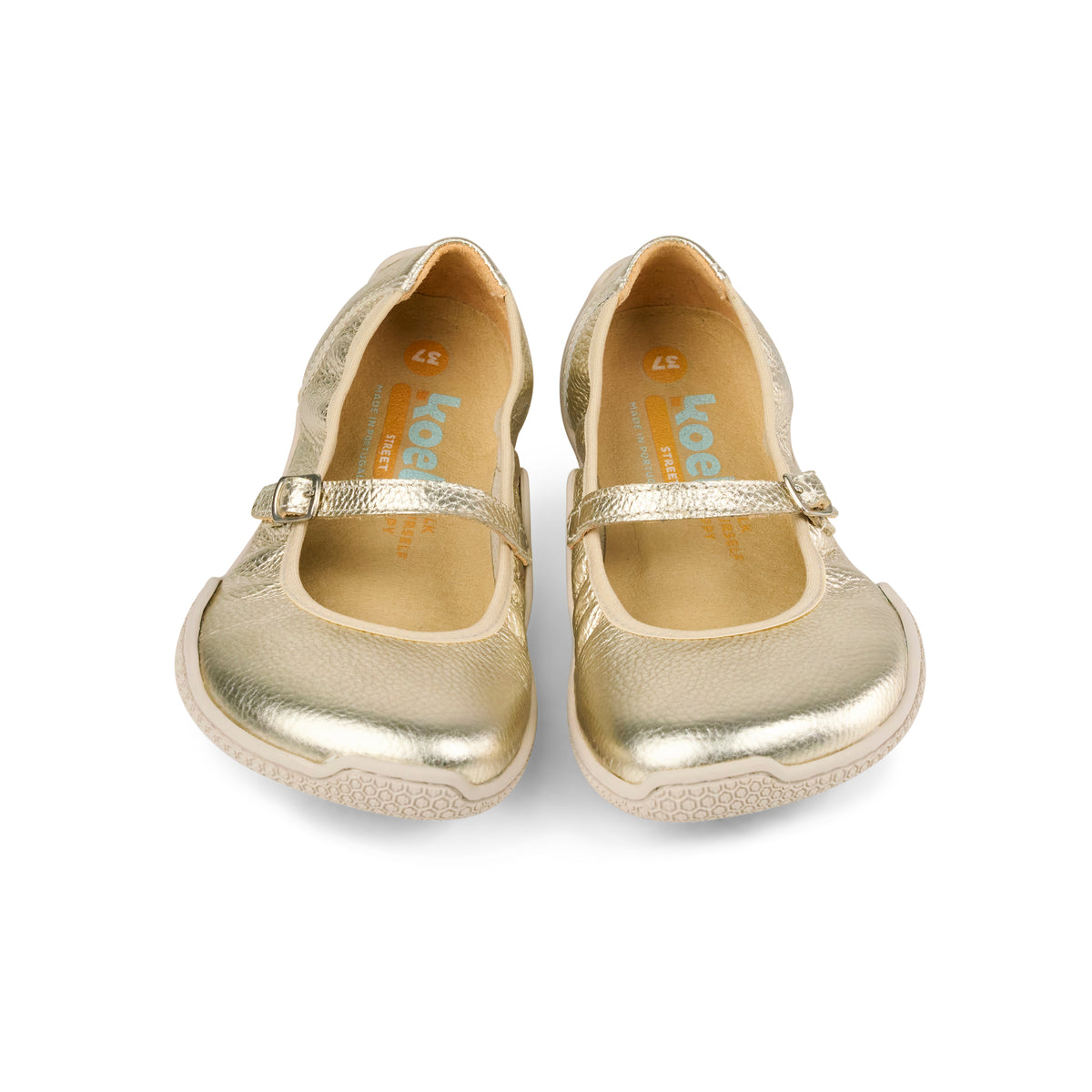 Front view of KOEL gold flats showing rounded toes and adjustable straps
