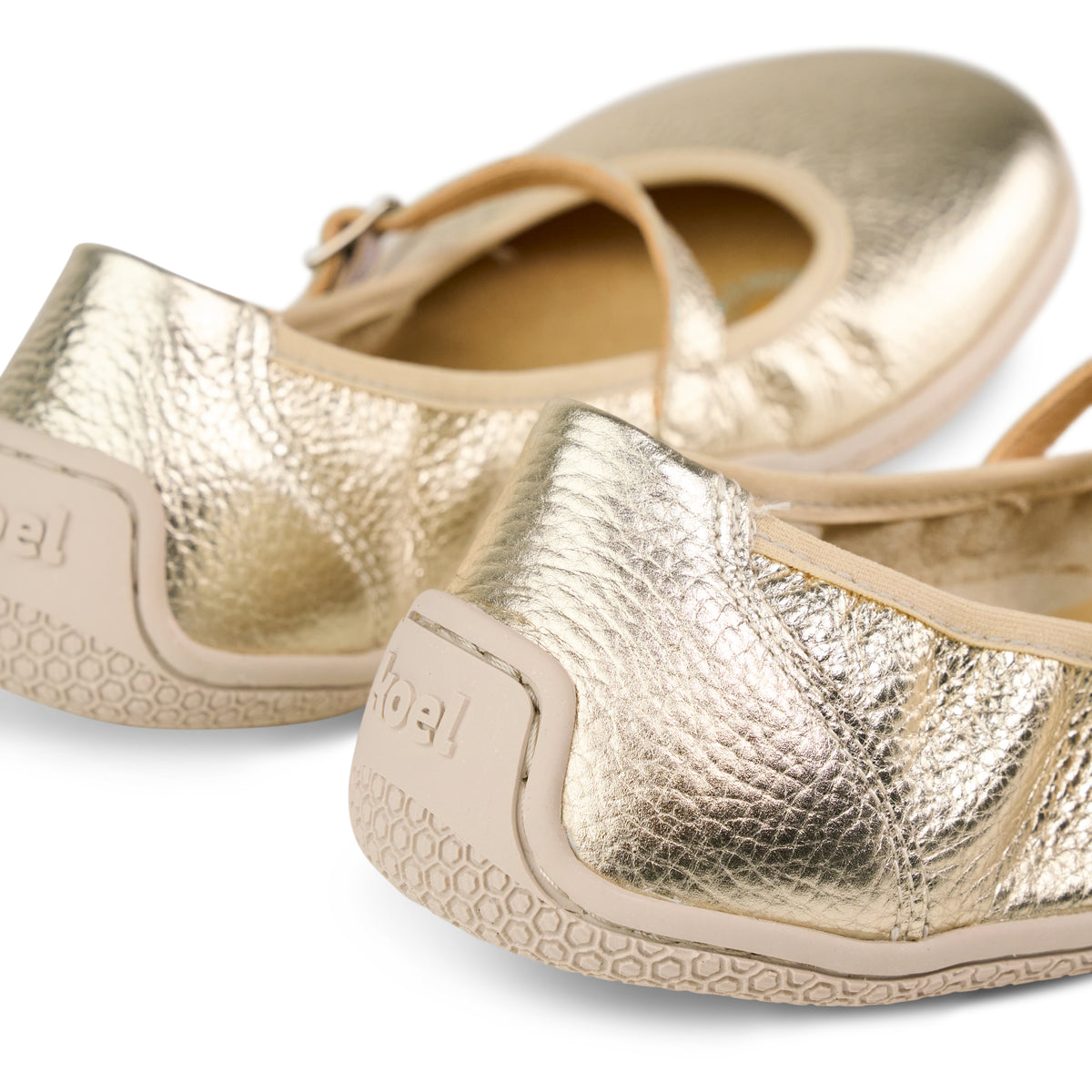 Close-up of metallic gold flat heels and textured uppers with patterned soles